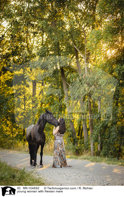 young woman with friesian mare / RR-104692