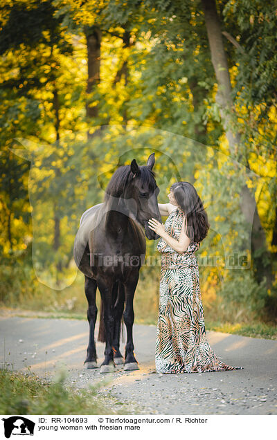 young woman with friesian mare / RR-104693