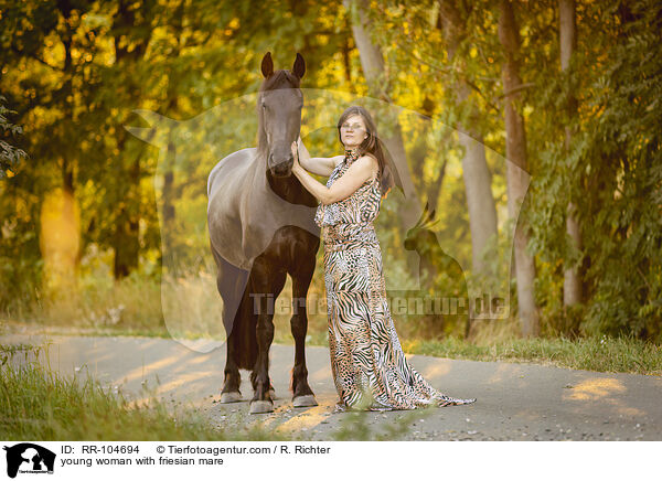 young woman with friesian mare / RR-104694