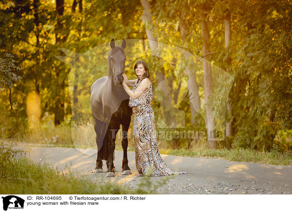 young woman with friesian mare / RR-104695