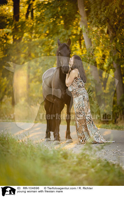 young woman with friesian mare / RR-104696