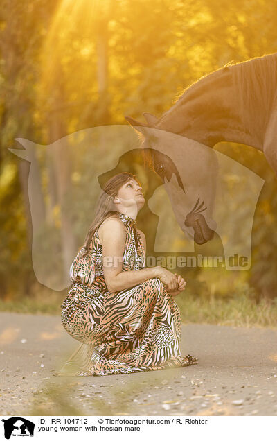young woman with friesian mare / RR-104712