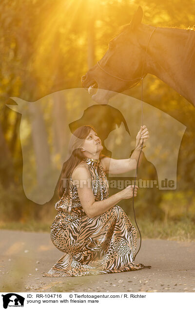 young woman with friesian mare / RR-104716