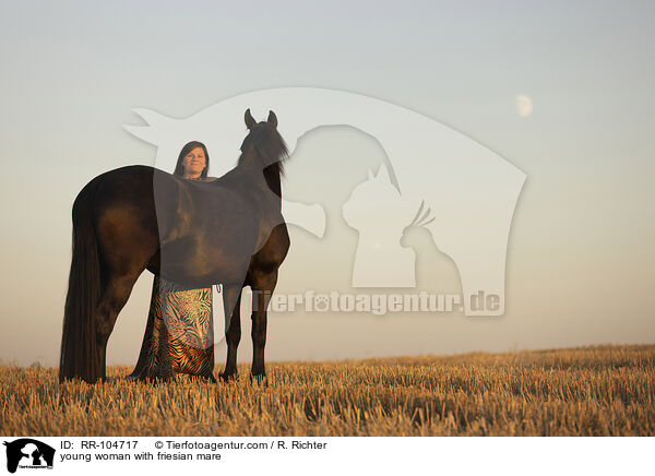 young woman with friesian mare / RR-104717