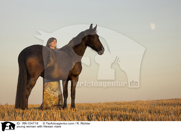 young woman with friesian mare / RR-104718