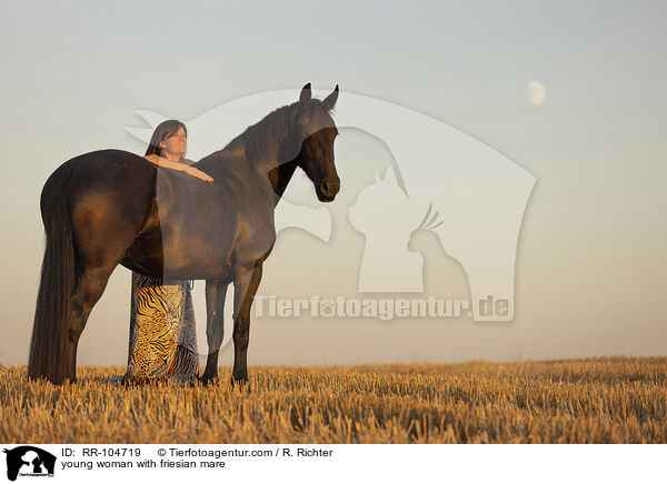 young woman with friesian mare / RR-104719