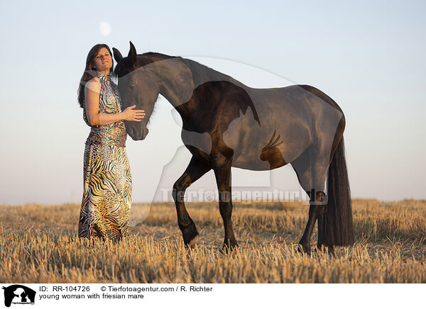 young woman with friesian mare / RR-104726
