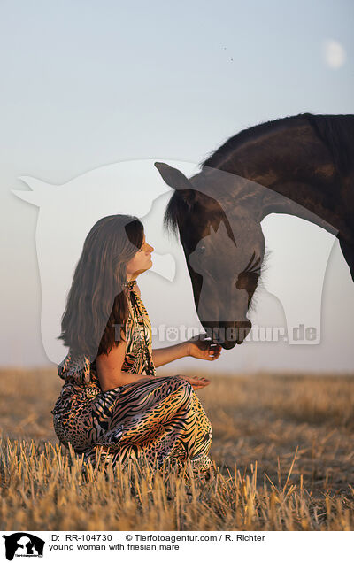 young woman with friesian mare / RR-104730