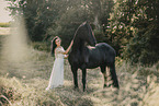 young woman in dress with frisian horse